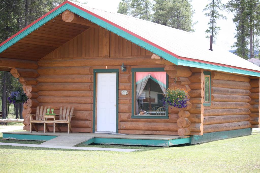 a log cabin with a porch and a door at Twin Peaks Hotel Cabins in Valemount