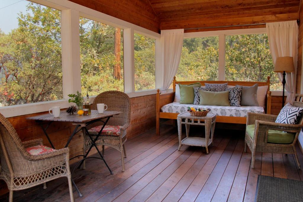 eine Veranda mit einem Bett, einem Tisch und Fenstern in der Unterkunft Coho Cottages in Willow Creek