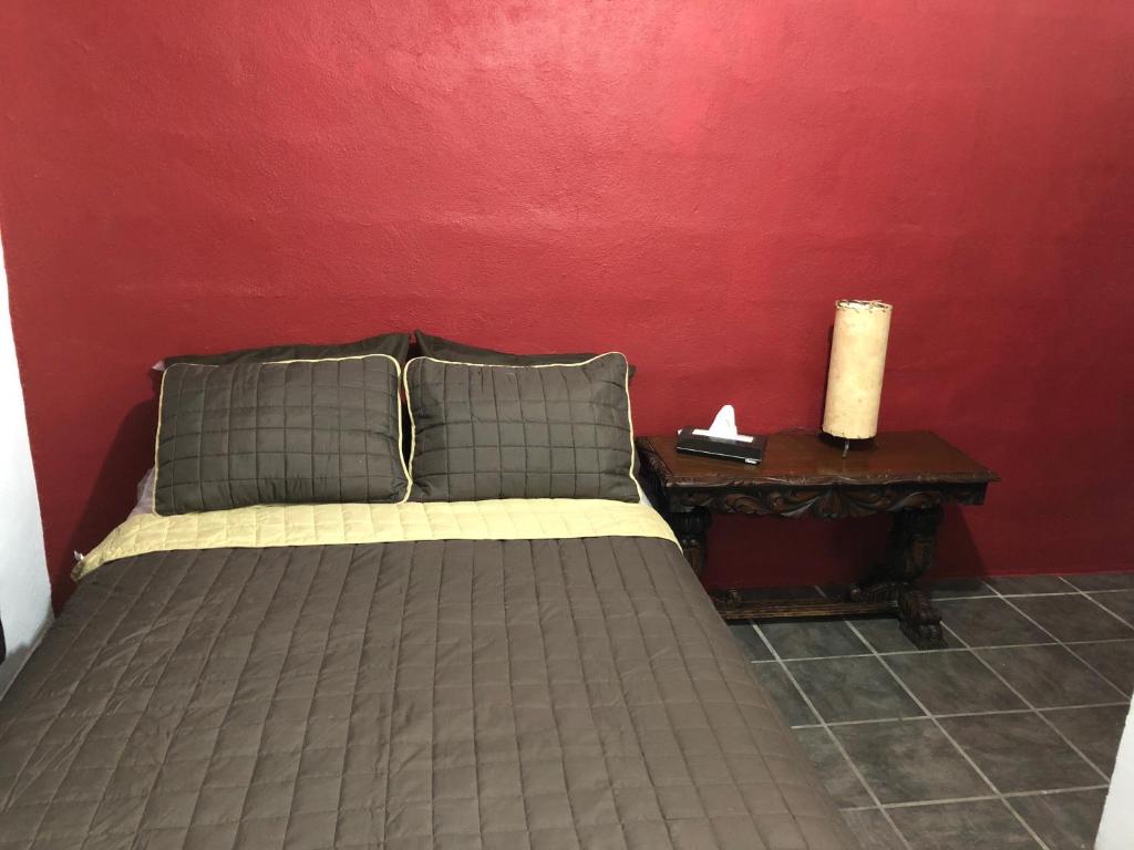 a bedroom with a bed and a red wall at Estancia del Sol in Cabo San Lucas