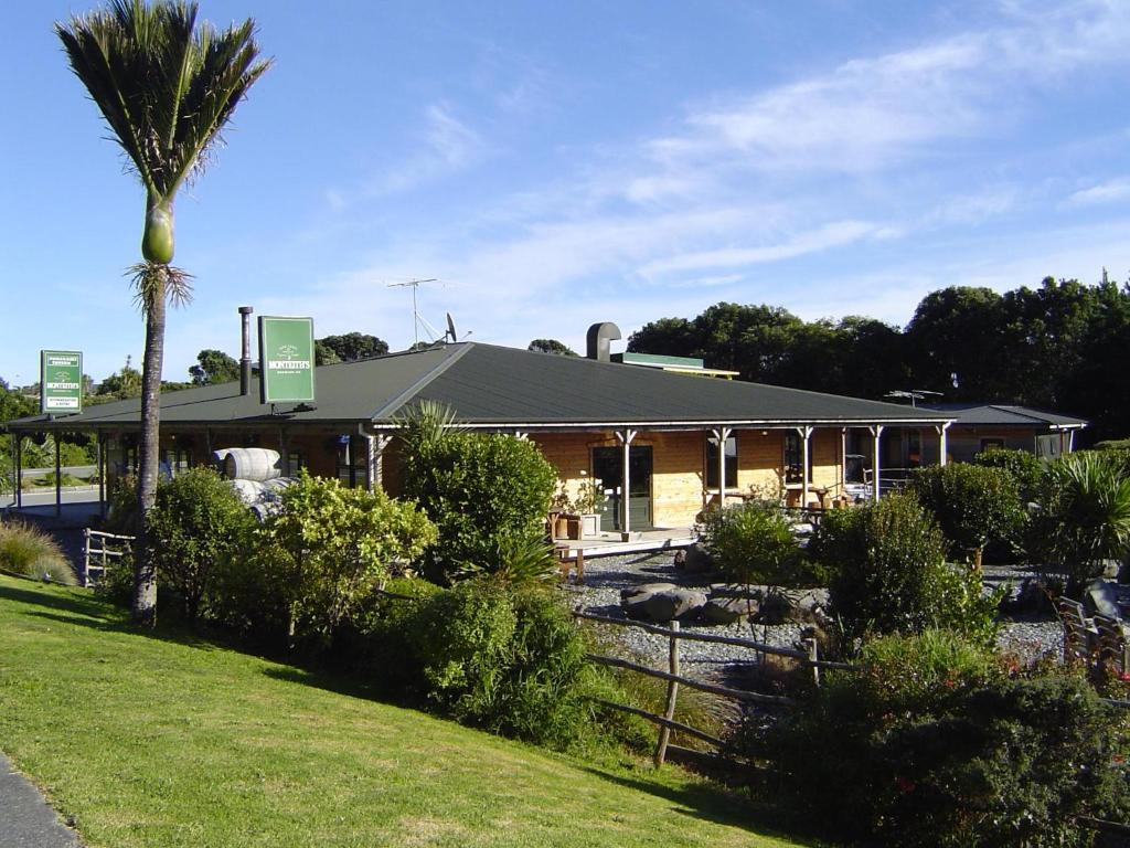 a building with a palm tree in front of it at Punakaiki Rocks Hotel & Garden Bar in Punakaiki