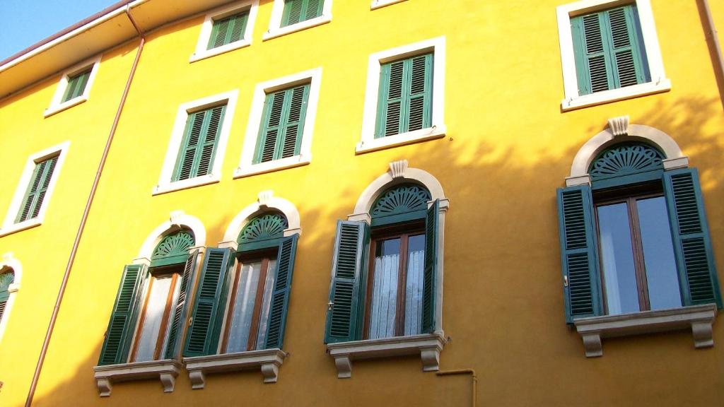 un edificio amarillo con persianas verdes. en Romeo Design Rooms en Verona