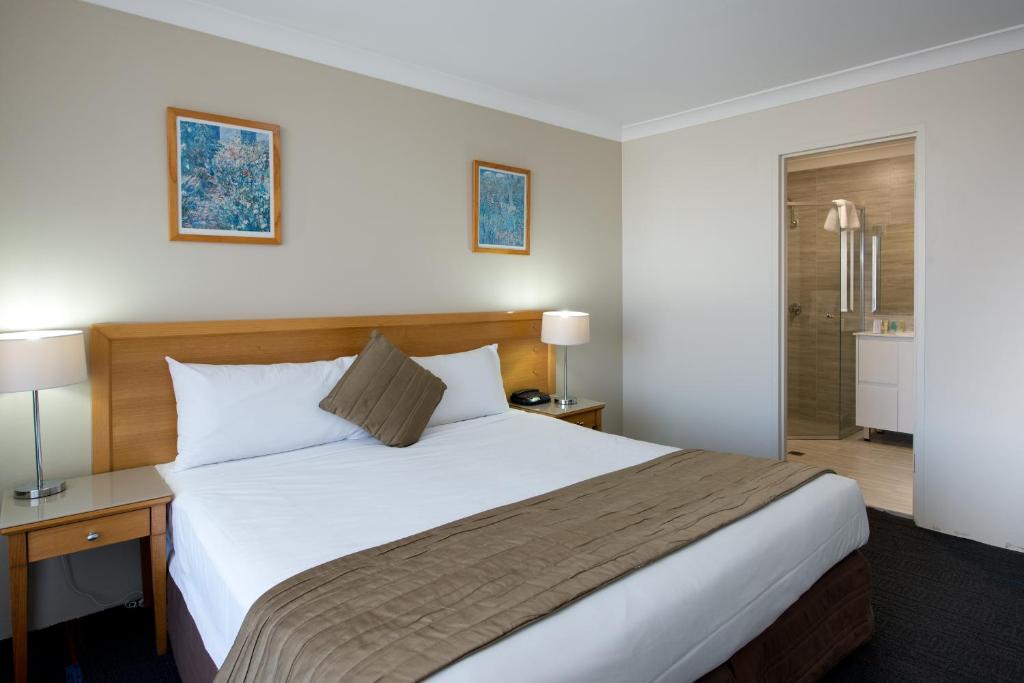 a hotel room with a large bed and a bathroom at APX Parramatta in Sydney