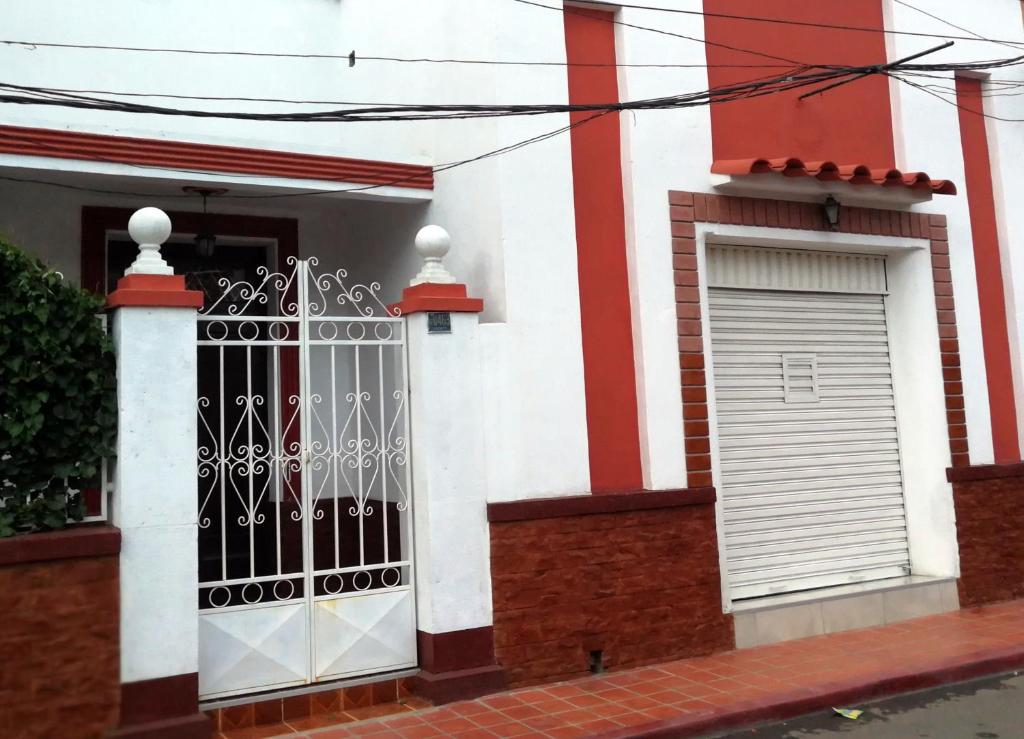 a white and red house with a gate and a door at Tierra Nuestra in Tarija