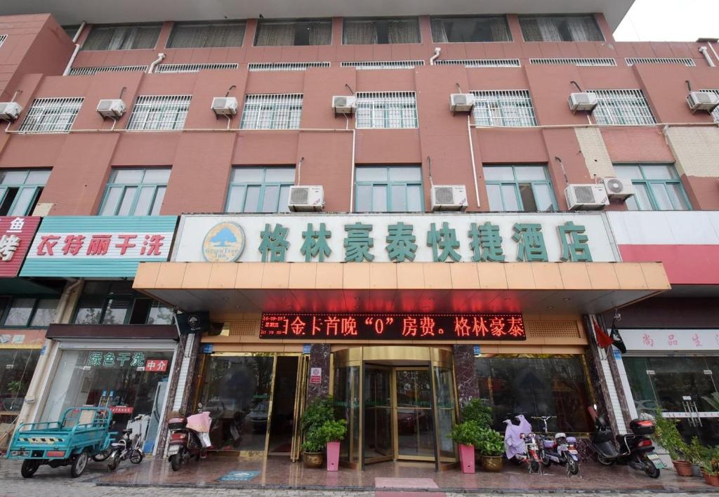 een groot rood gebouw met Chinees schrift erop bij GreenTree Inn Jiangsu Taizhou Jiangyan Bus Station Express Hotel in Taizhou