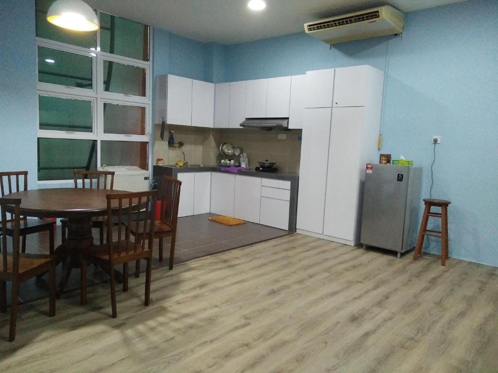 a kitchen and dining room with a table and a refrigerator at Xenia Homestay in Kuching
