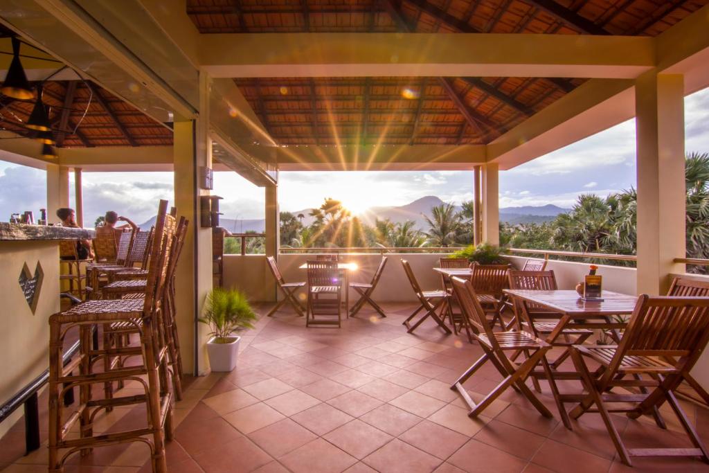 a patio with tables and chairs and a view of the mountains at Karma Traders Kampot in Kampot