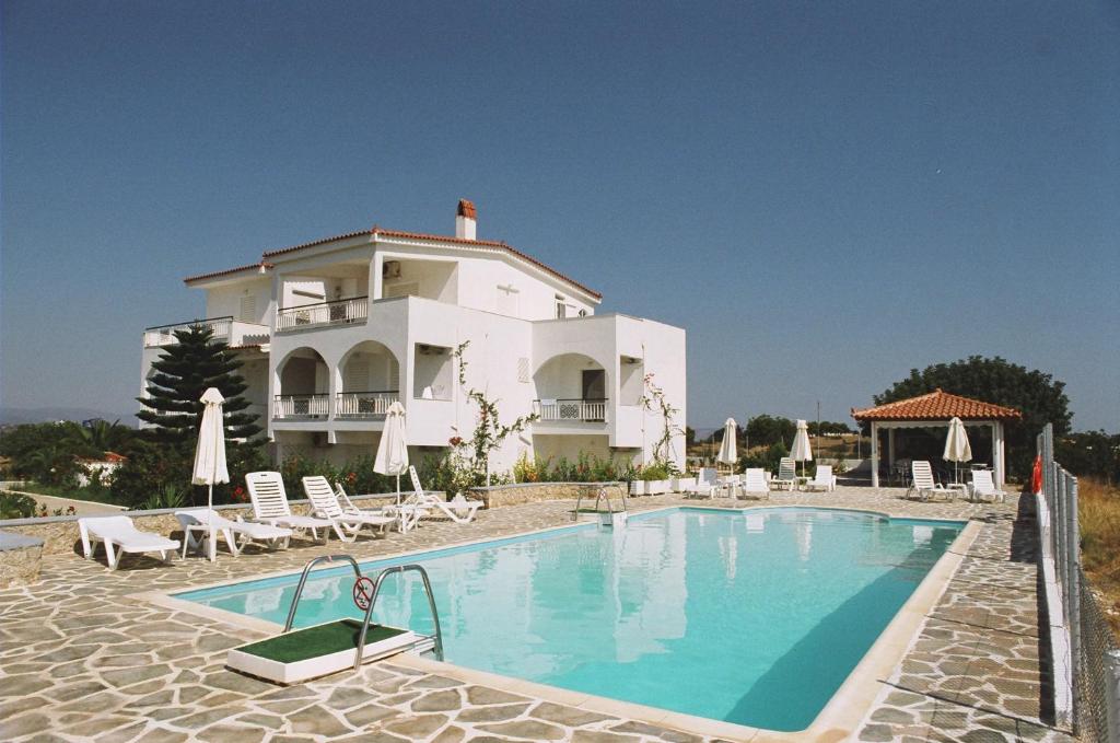 a large house with a swimming pool in front of it at Long View Apartments in Porto Heli