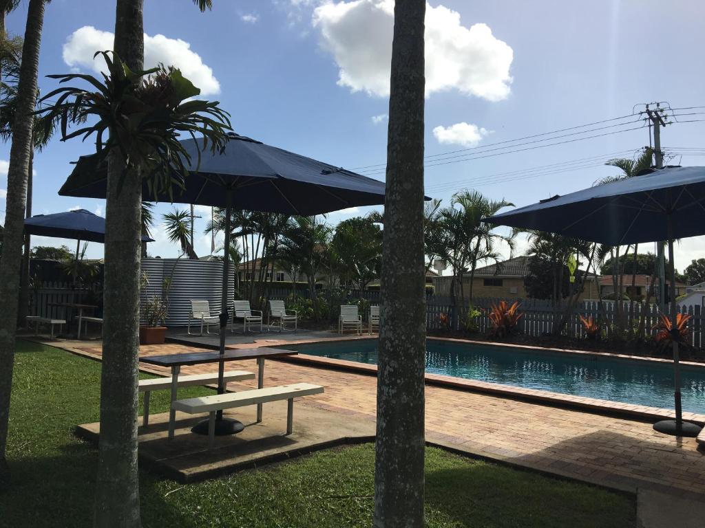 a swimming pool with a picnic table and umbrellas at BIG4 Cane Village Holiday Park in Bundaberg