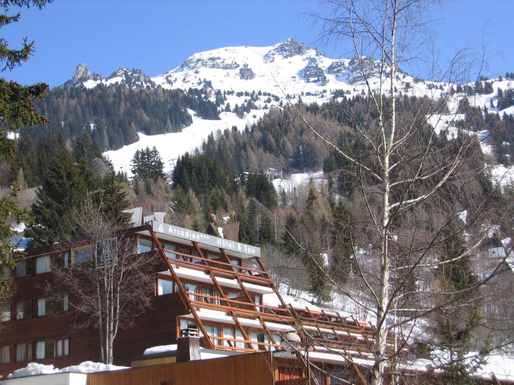 un edificio con una montaña cubierta de nieve en el fondo en Hôtel Arcadien en Arc 1600