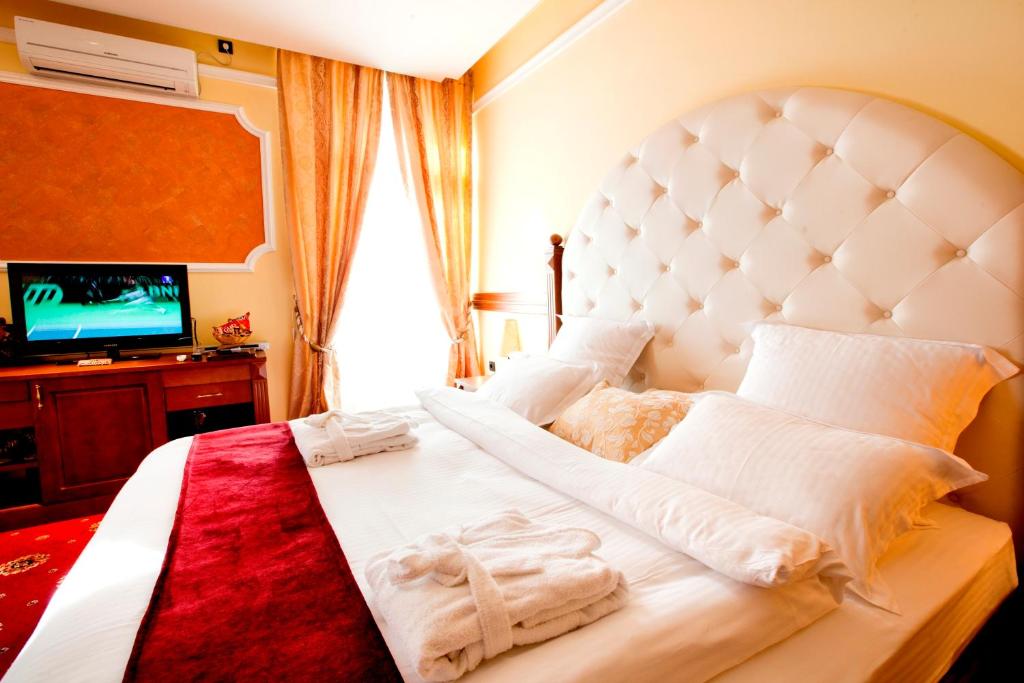 a bedroom with a large white bed and a television at Manjež Centar in Belgrade