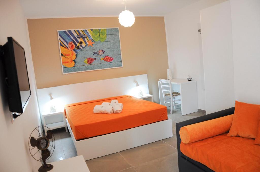 una camera con un letto arancione e un divano di Torre Chianca GMA Tourism a Porto Cesareo