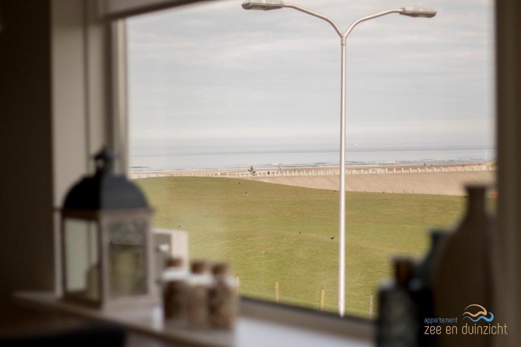 Katwijk aan ZeeにあるAppartement Zee en Duinzicht 78のビーチの景色を望む窓、通りの光