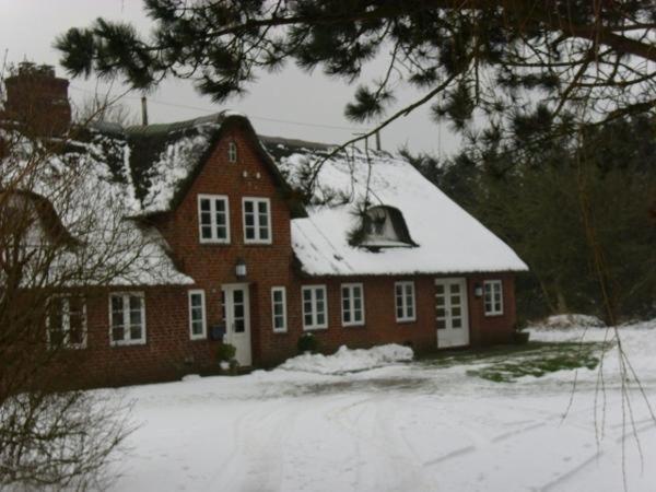 a red house with snow on top of it at Hackerhof-Westwohnung in Morsum