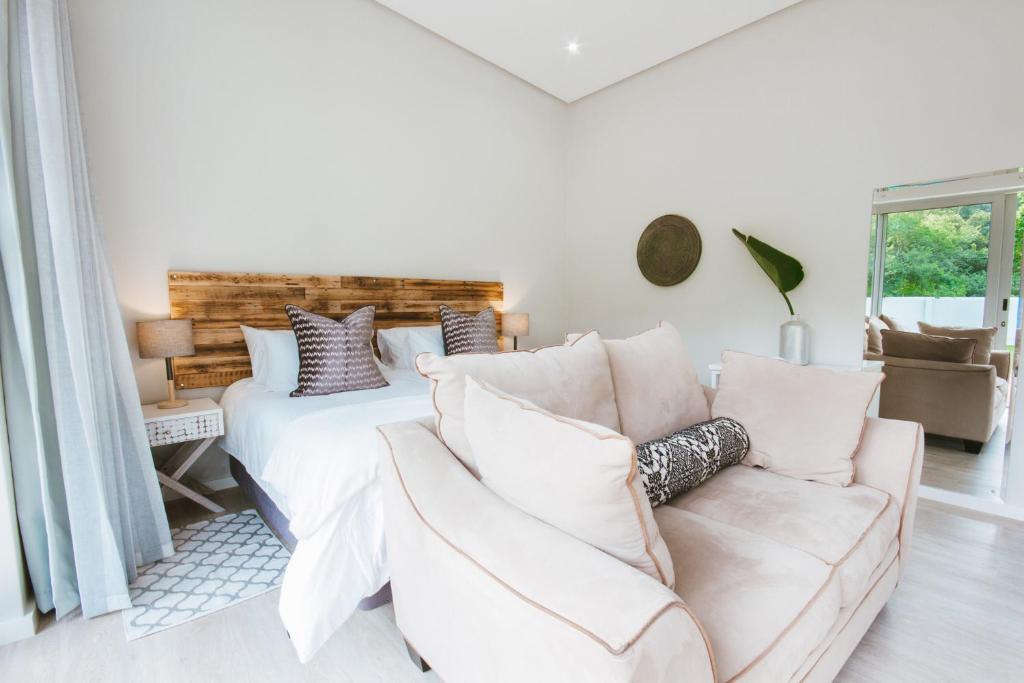a white bedroom with a bed and a couch at A Riverbed Guesthouse in Swellendam