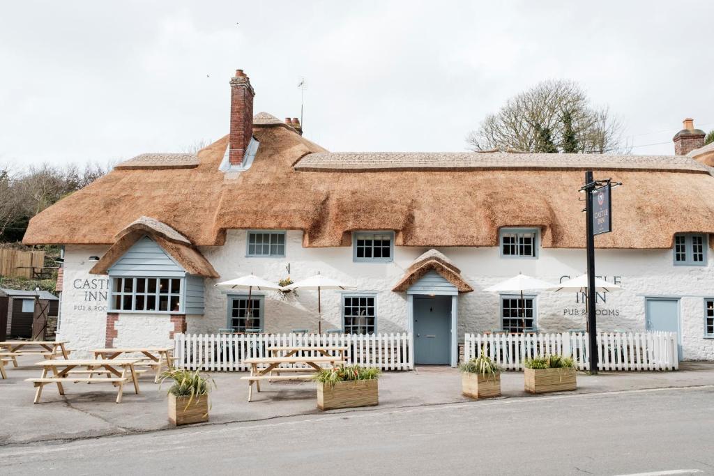 a building with a thatched roof with picnic tables at Castle Inn in West Lulworth