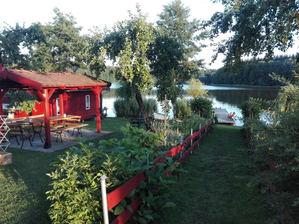 una cabaña roja junto a un lago con una mesa de picnic en Agro-Tur Domki w Szuwarach en Kuty