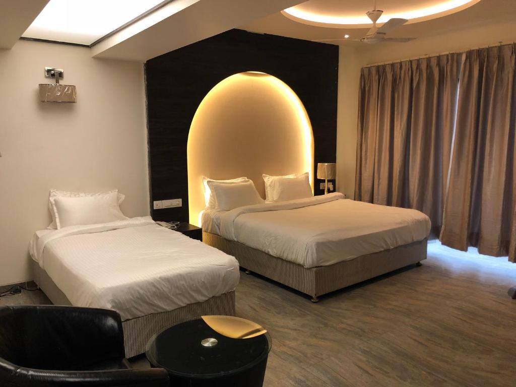 een hotelkamer met 2 bedden en een groot raam bij Hotel Sharanam in Shegaon