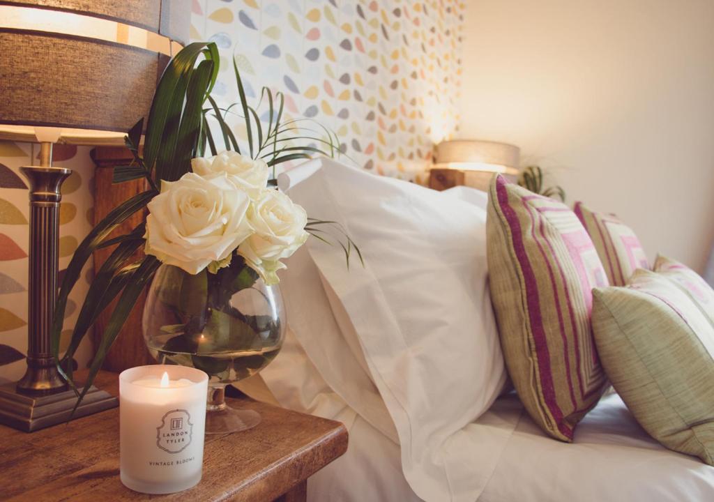 a candle and a vase with flowers on a table at Windy Harbour restaurant and accommodation in Glossop