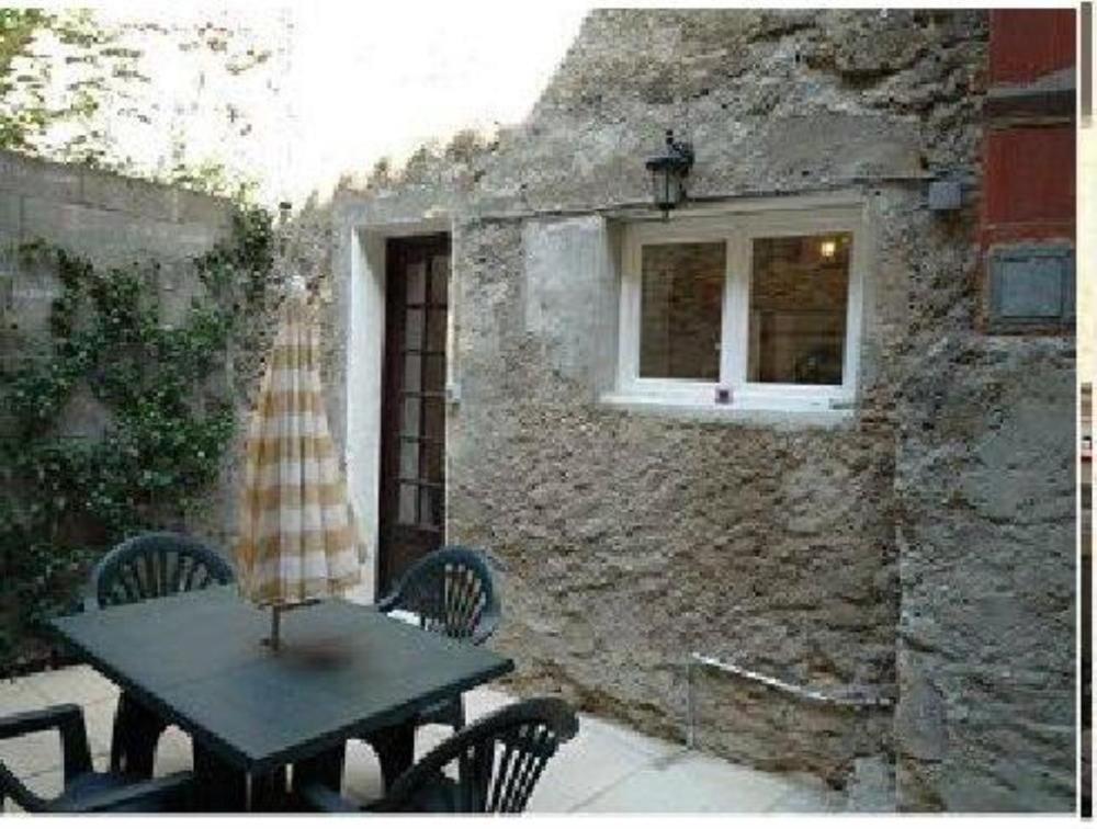 une table et des chaises devant un mur en pierre dans l'établissement Maison près Cité de Carcassonne, à Villalier