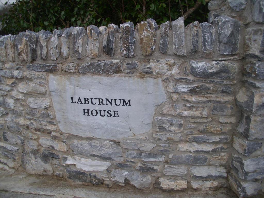 Una pared de piedra con un cartel que lee la casa de los laureles en Laburnum B&B, en Kenmare