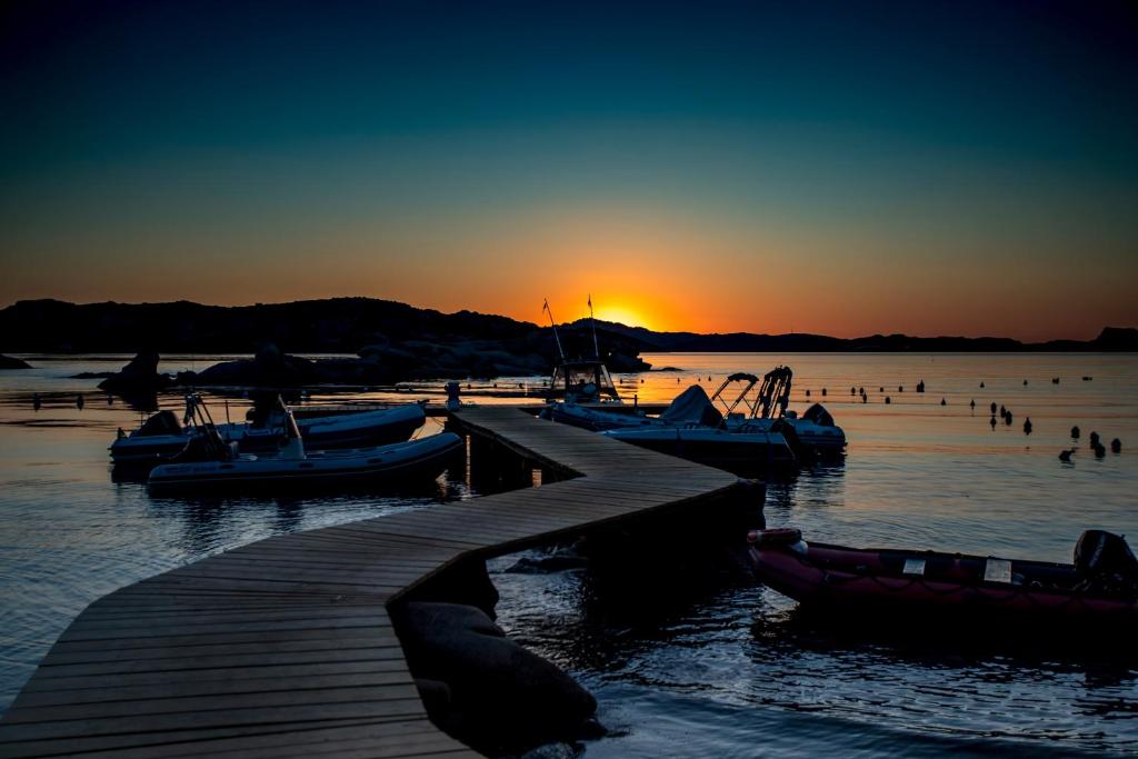 ein Dock mit Booten im Wasser bei Sonnenuntergang in der Unterkunft Camping Baia Saraceno in Palau