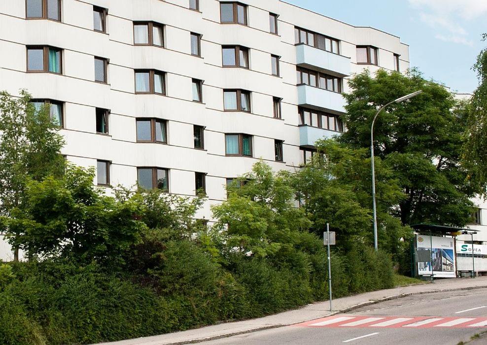 un gran edificio blanco con árboles frente a una calle en SOVEA Hotel - Braunau, en Braunau am Inn