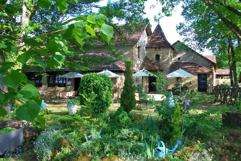 a garden in front of a house with umbrellas at Auberge de Castel-Merle in Sergeac