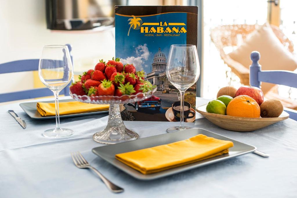 a table with a plate of fruit and wine glasses at La Habana Apart Hotel in Lloret de Mar