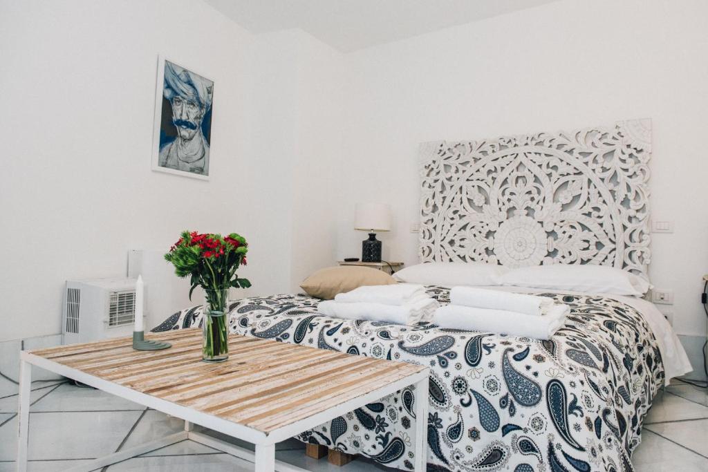 1 dormitorio con 1 cama con un jarrón de flores sobre una mesa en L' Ambasciata Gaeta en Gaeta