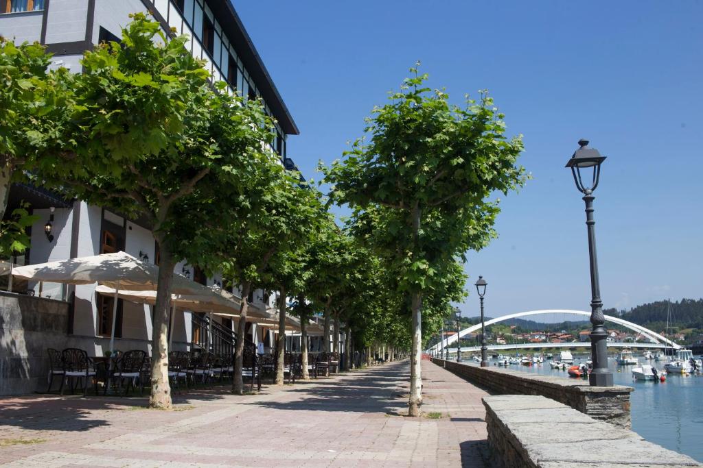 a street with trees on the side of a canal at Hotel Boutique Bahía de Plentzia in Plentzia