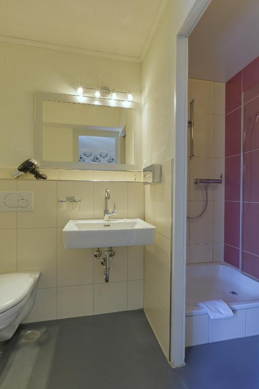 a bathroom with a sink and a tub and a toilet at Alplodge in Interlaken