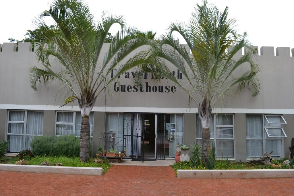 a building with two palm trees in front of it at Travel North Guesthouse in Tsumeb