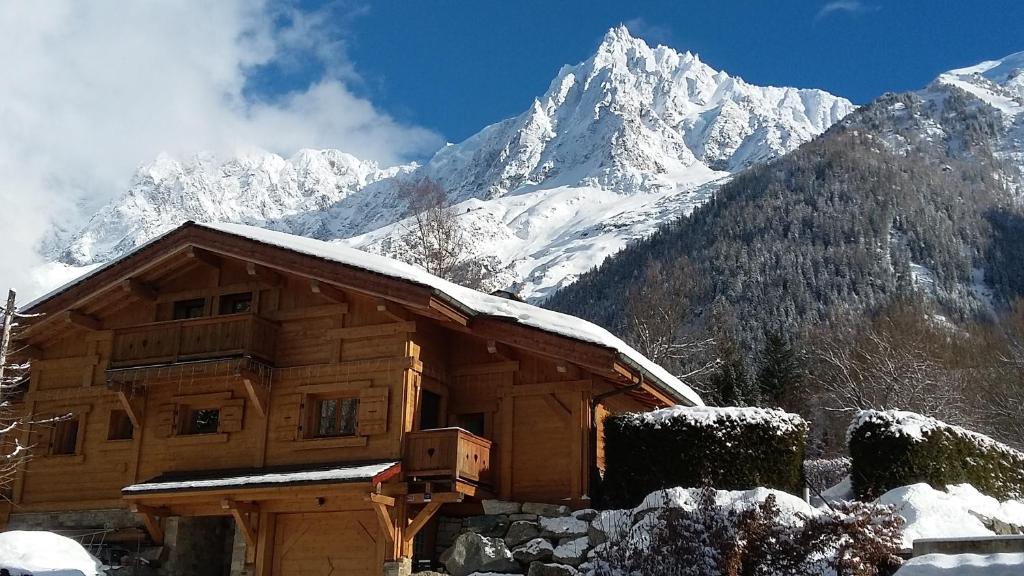 una cabaña de madera con una montaña cubierta de nieve en el fondo en Chalet Kidou, en Chamonix-Mont-Blanc