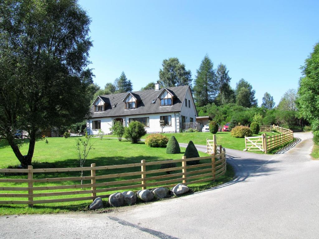 une maison avec une clôture en bois devant une cour dans l'établissement Carn A Chuilinn, à Fort Augustus