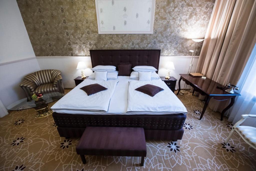 a bedroom with a bed and a chair and a table at Golden Royal Boutique Hotel & Spa in Košice