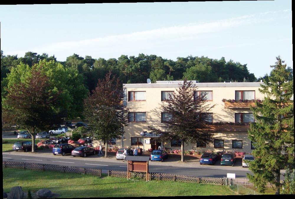 a building with cars parked in a parking lot at Hotel-Restaurant Fuchs in Handeloh