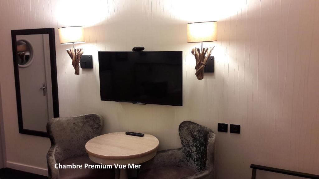 a room with two chairs and a table and a flat screen tv at Hôtel Les Brises in La Rochelle