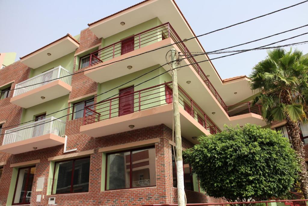 a building with a palm tree in front of it at Hotel Santos Pina in São Filipe