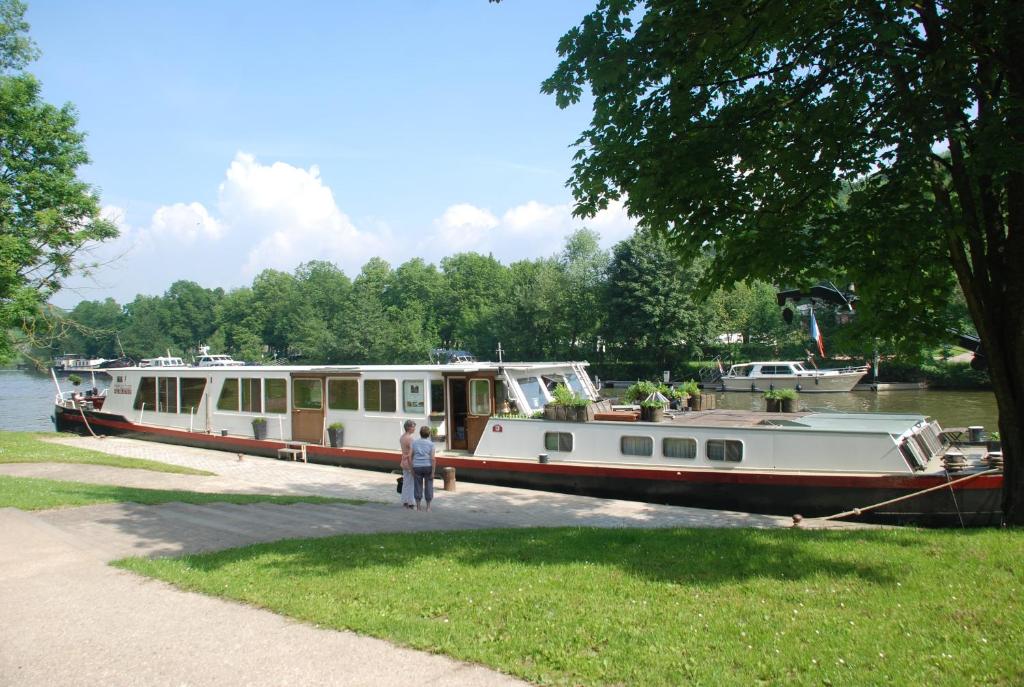 a man standing next to a boat on the water at Péniche d'hôtes MS Elisabeth in Namur