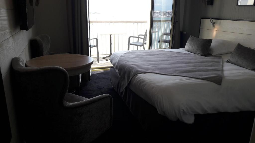 a bedroom with a bed and a table and a window at Hôtel Les Brises in La Rochelle