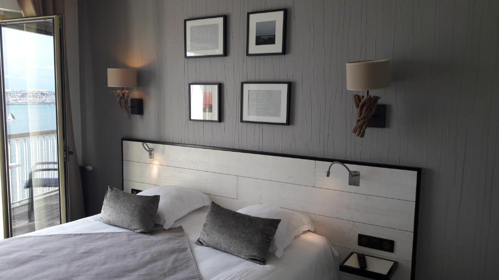 a bedroom with a white bed with two pillows at Hôtel Les Brises in La Rochelle