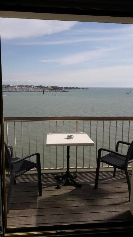 a table and two chairs on a deck with the water at Hôtel Les Brises in La Rochelle