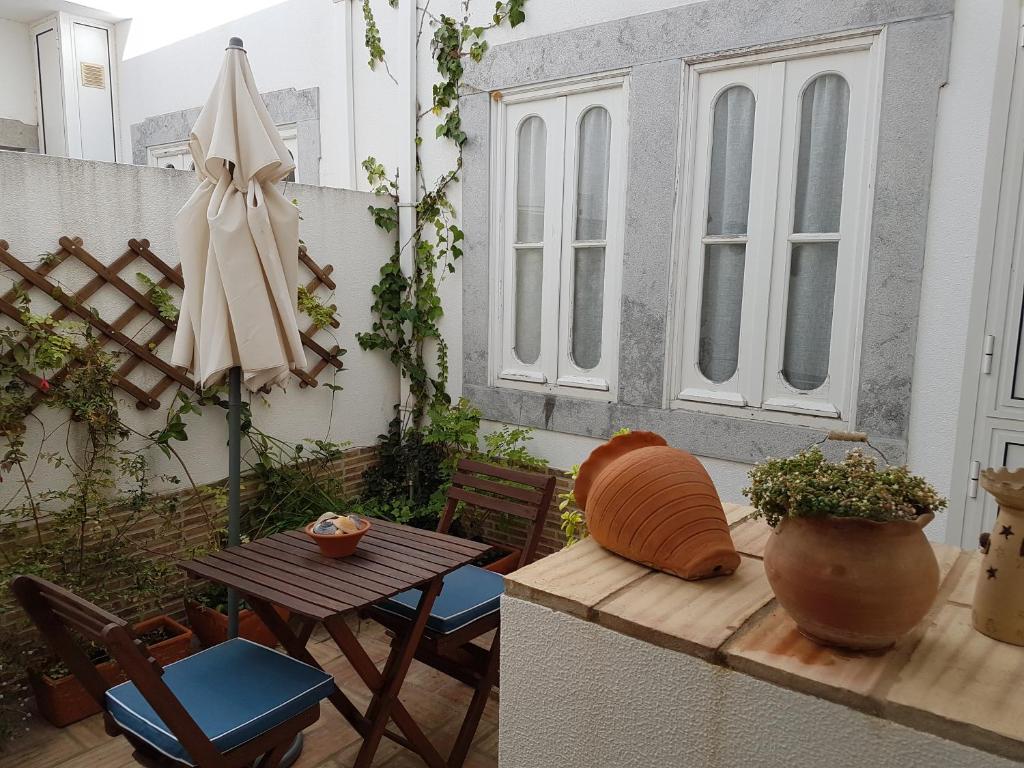 un patio con mesa, silla y sombrilla en Cozy Home, en Tavira