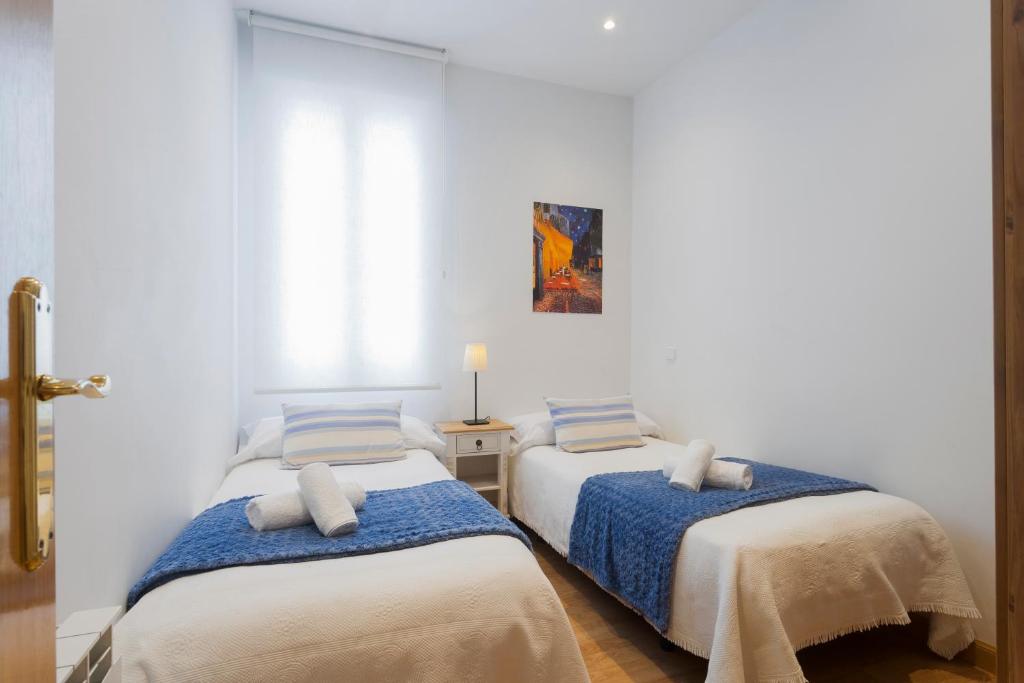 zwei Betten in einem Zimmer mit weißen Wänden in der Unterkunft Cosy Apartment Malasaña in Madrid