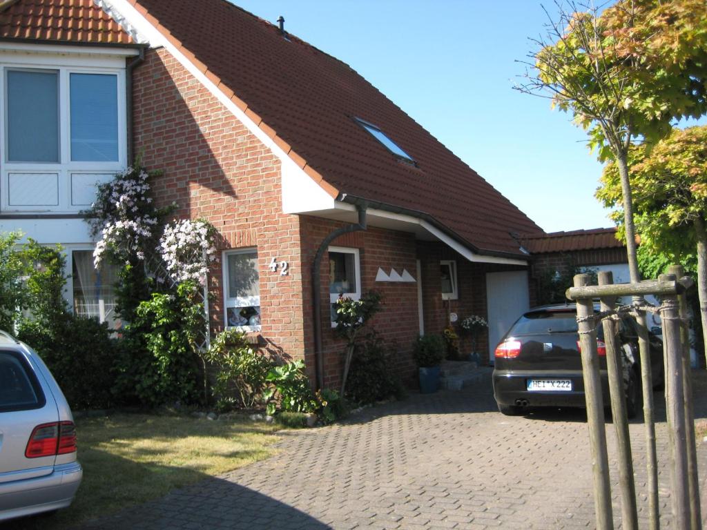 a brick house with two cars parked in the driveway at Haus Pistorius in Büsum