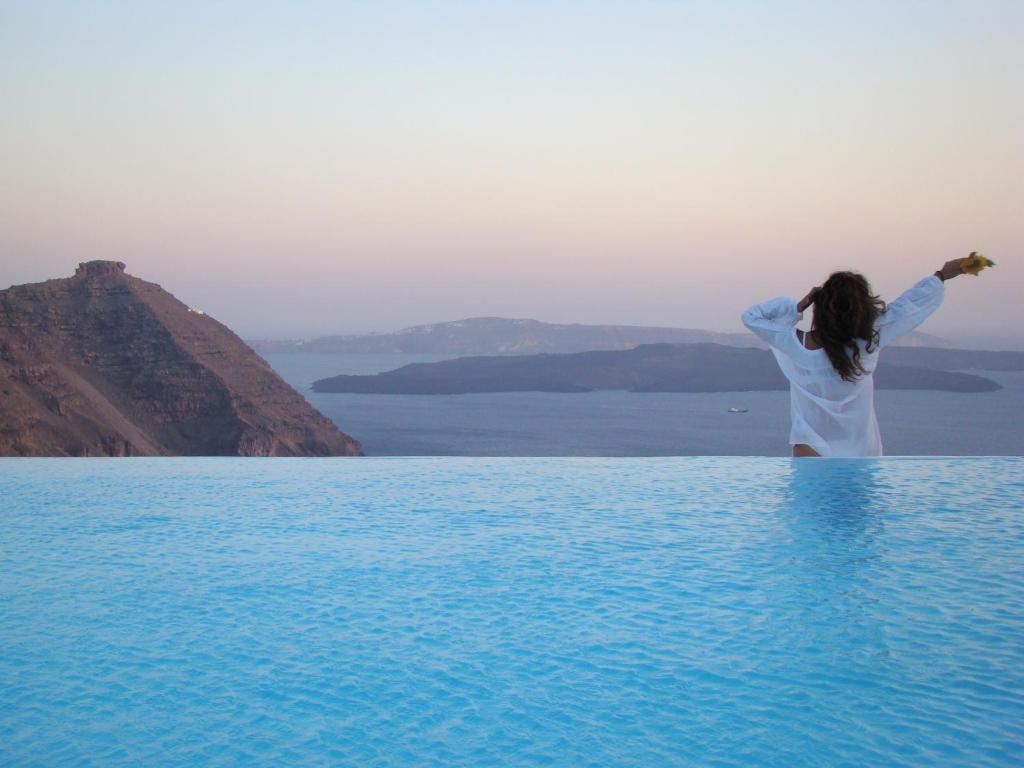 a woman standing in the middle of a body of water at Aenaon Villas in Imerovigli