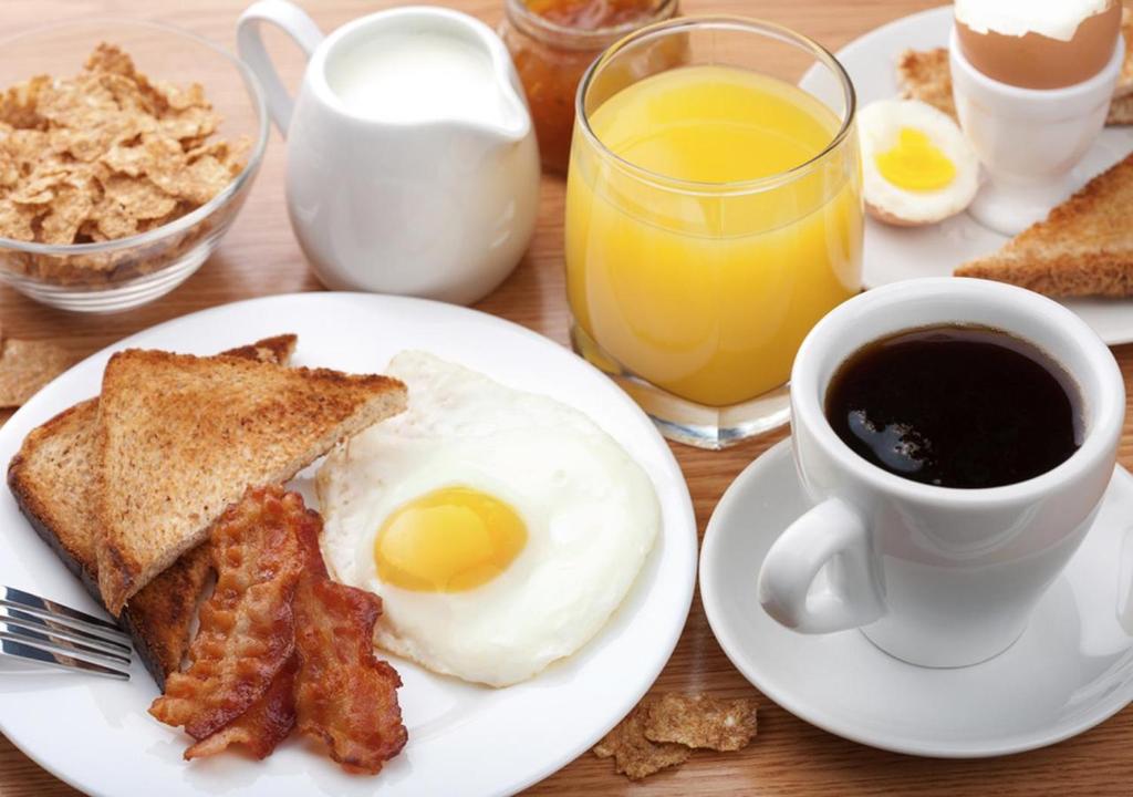 a breakfast plate with eggs and bacon and a cup of coffee at Hôtel Club mmv Le Flaine *** in Flaine