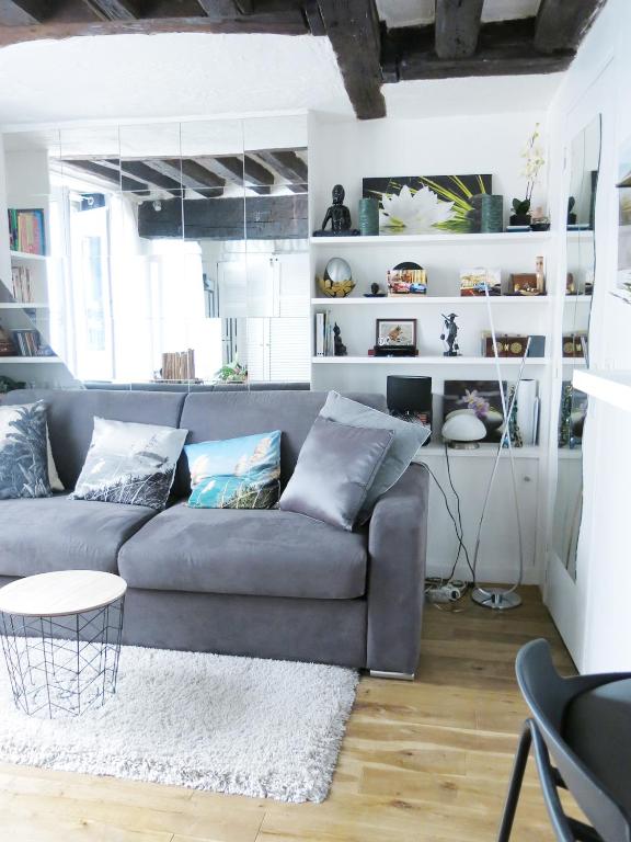 a living room with a gray couch and white shelves at Studio Marais Charlot CityCosy in Paris
