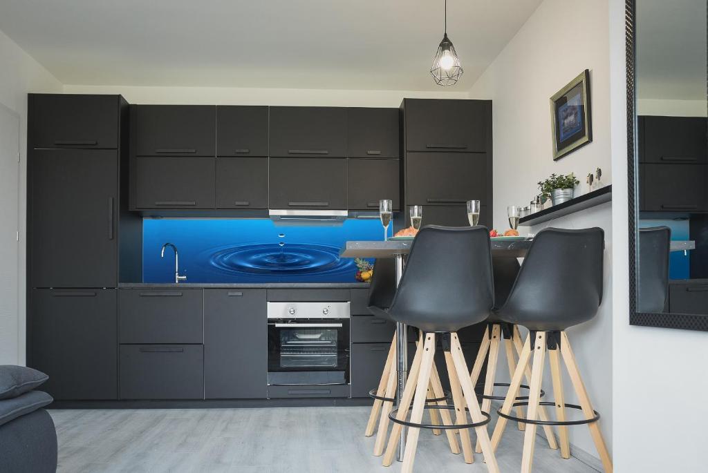 een keuken met zwarte kasten en zwarte barkrukken bij Drop (in) Apartment in Zagreb