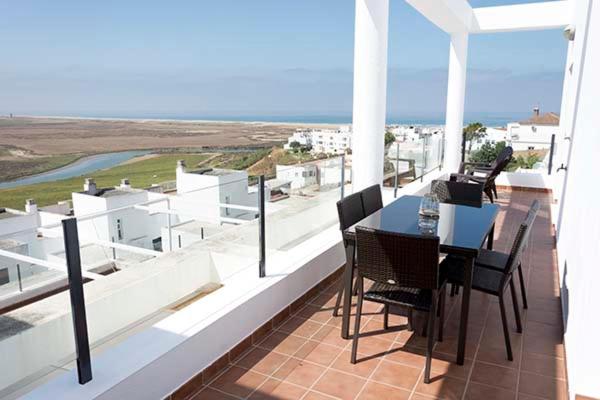 een tafel en stoelen op een balkon met uitzicht op de oceaan bij conilsolymar ático in Conil de la Frontera